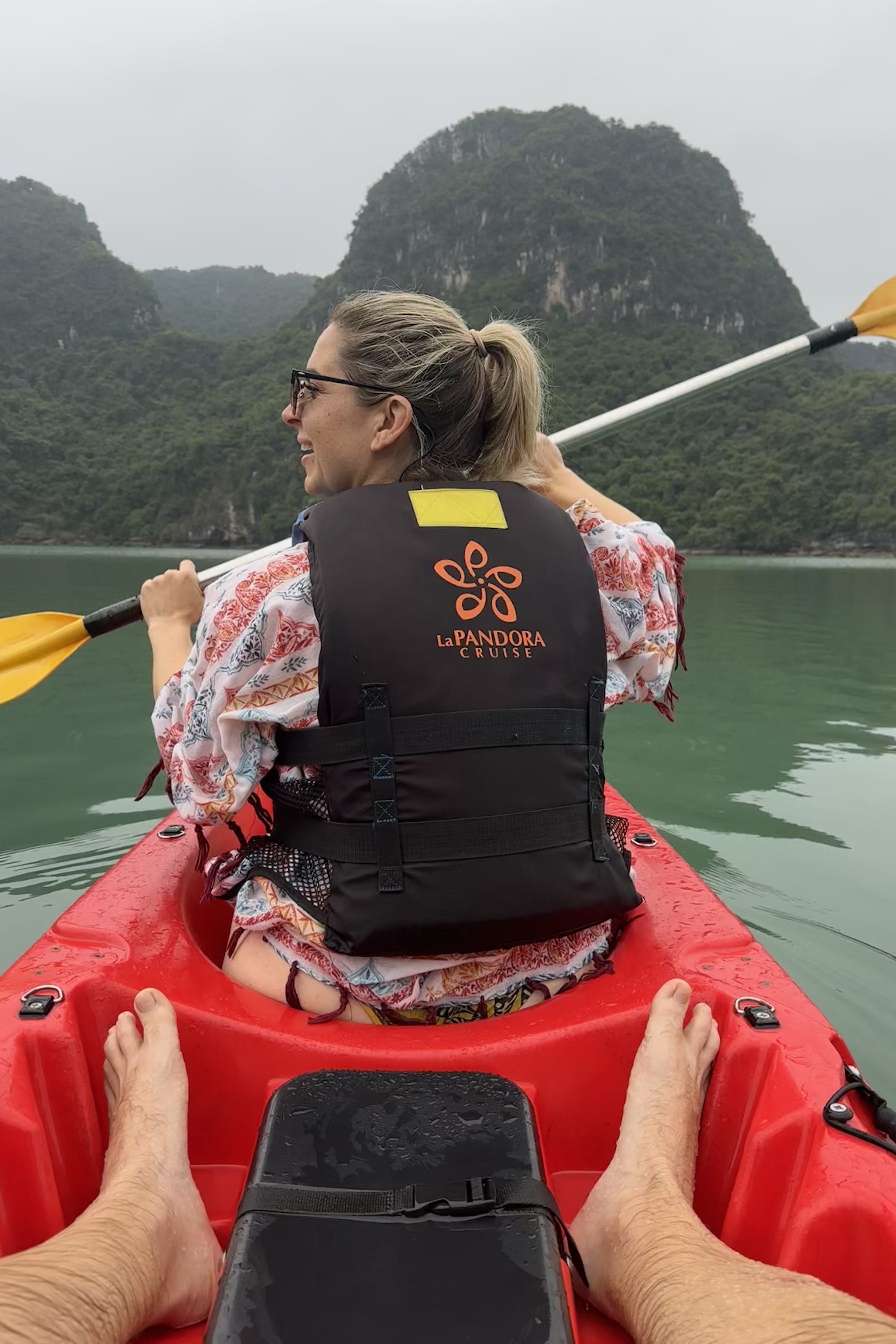 Nathalie kayaking in the serene waters of Ha Long Bay, surrounded by towering limestone cliffs and lush greenery, showcasing a tranquil moment during her adventure in Lan Ha Bay.
