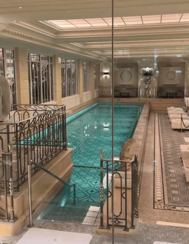 Luxurious indoor swimming pool area with ornate design, glass walls, and comfortable seating surrounding the pool.